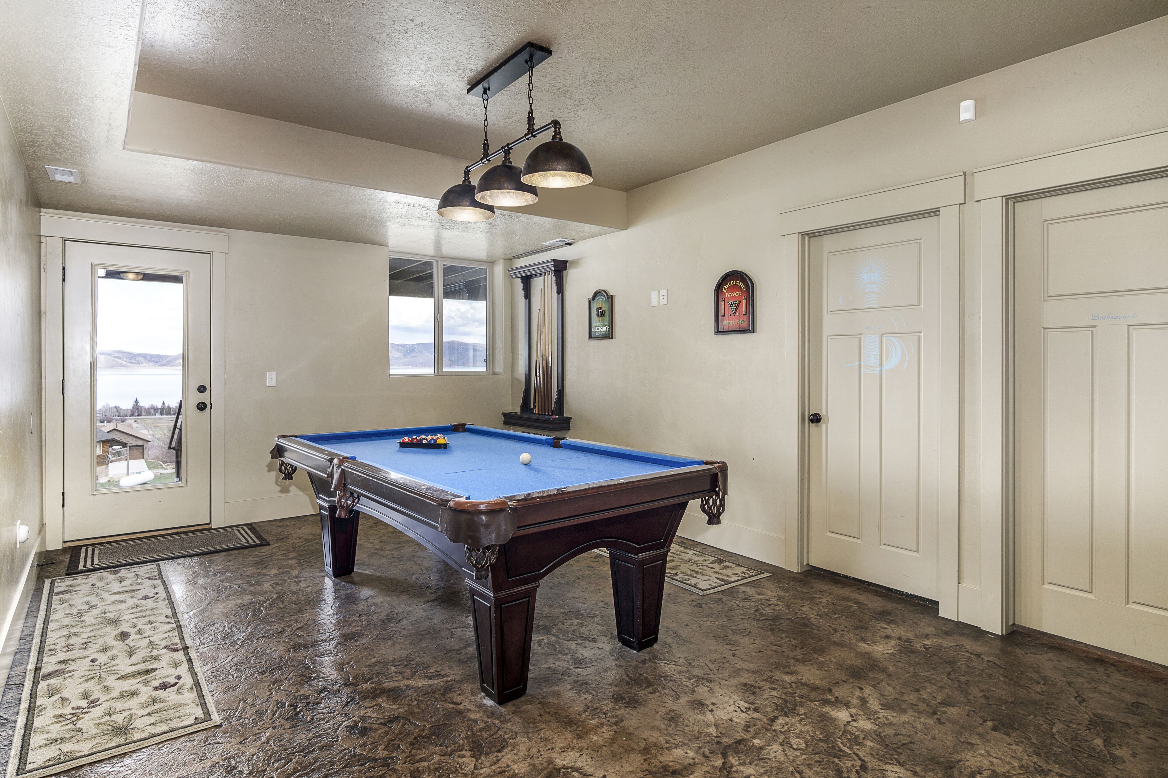 Una mesa de billar en una habitación con vistas, una puerta y una ventana.