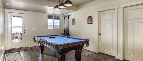 Una mesa de billar en una habitación con vistas, una puerta y una ventana.