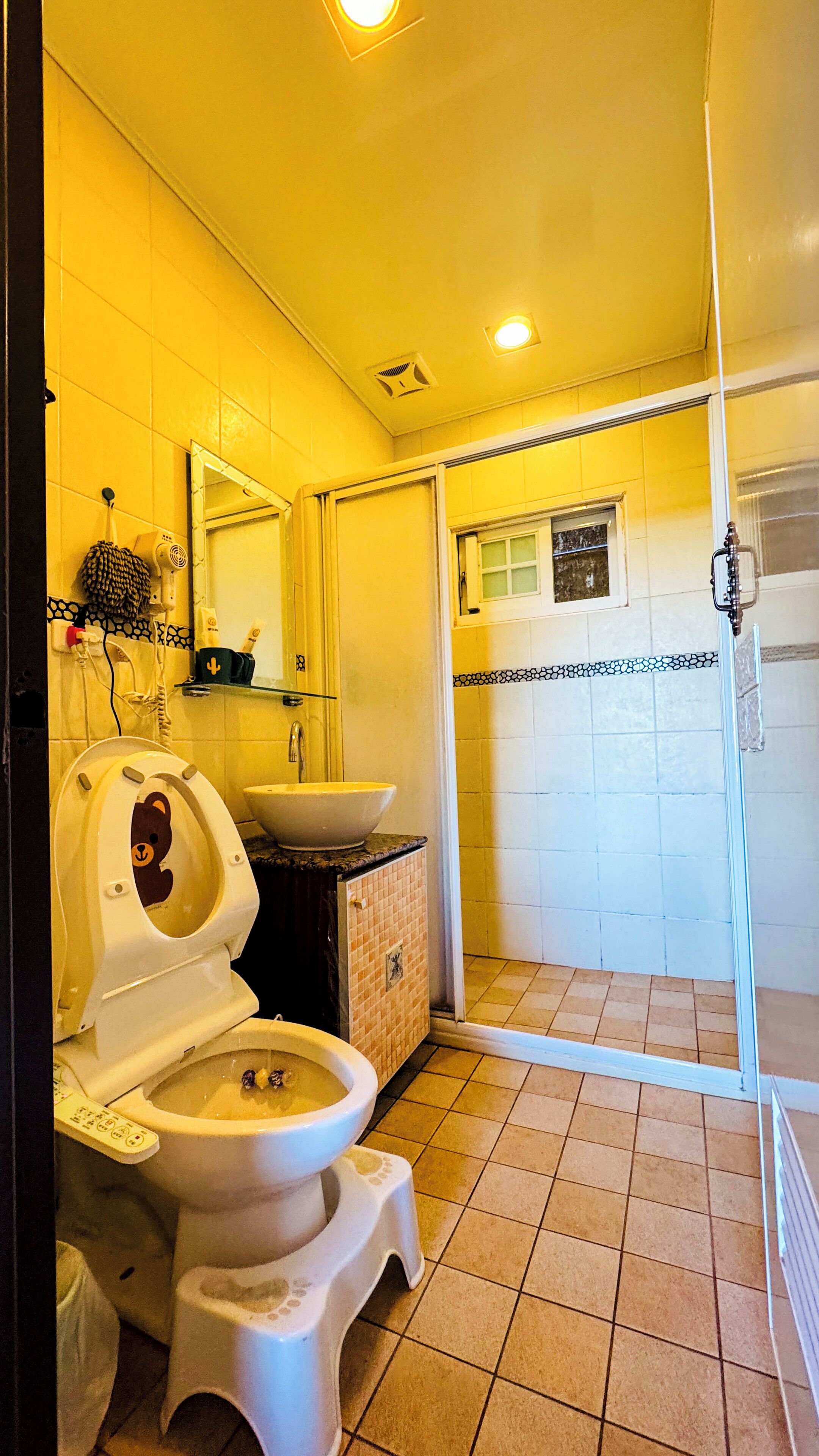 Et badeværelse med toilet, vask og bruser.