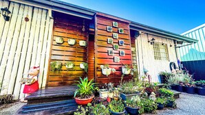 Un bâtiment en bois avec une pancarte d’accueil, des plantes en pot et un espace aménagé en jardin.