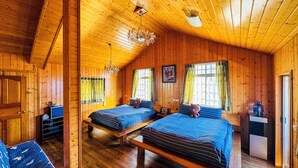 Une cabane en bois avec deux lits, un lustre et un distributeur d’eau.