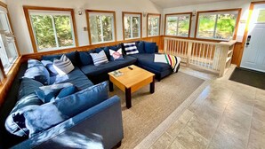 A spacious living room with a large sectional sofa, a wooden coffee table, and a ceiling fan.