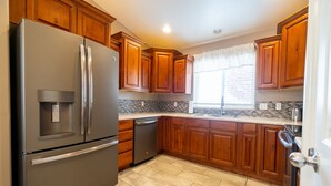 Una cocina con armarios de madera, un refrigerador de acero inoxidable y un lavavajillas.