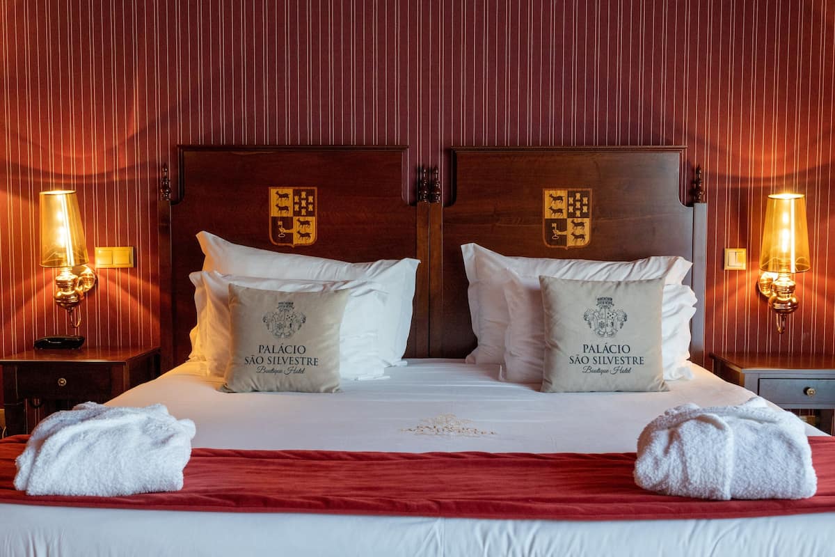 A double bed with two pillows, each labeled "Palácio São Silvestre Boutique Hotel."