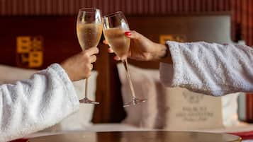 Two people toasting with champagne glasses at a round table in a room with a wooden panel wall.