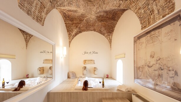 A luxurious bathroom with a large bathtub, a mirror, and a framed artwork on the wall.