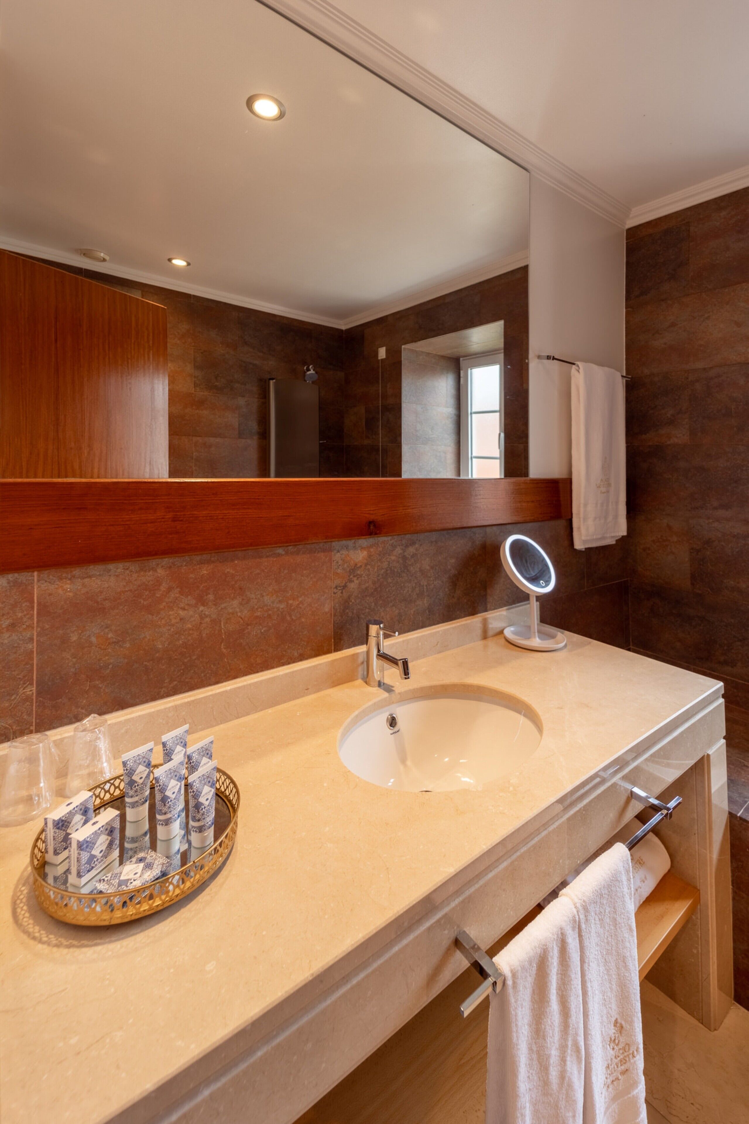 Une salle de bain moderne avec un double lavabo, un grand miroir et un meuble-lavabo agrémenté d’un plateau contenant des articles de toilette.