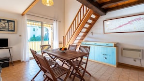 A dining area with a wooden table and chairs, a staircase, and a view of the outside. - Cosy apartment for 4 people with WIFI, A/C, TV and terrace (Cavalaire-sur-mer)