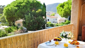 A balcony with a table set for breakfast, including croissants, fruit, and juice. - Cosy apartment for 4 people with WIFI, A/C, TV and terrace (Cavalaire-sur-mer)