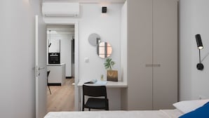 A modern bedroom with a bed, a desk, and a wardrobe. There is a small table with a plant and a handbag. - Alla Pescheria (Rovinj)