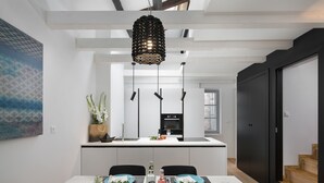 A modern kitchen with a central island, white cabinetry, and a hanging light fixture. - Alla Pescheria (Rovinj)