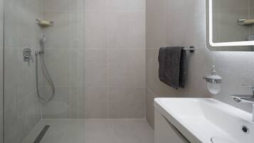 Un baño moderno con ducha, inodoro y lavamanos.
