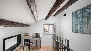 A modern loft bedroom with exposed wooden beams, a large window, a desk, and a black chair. - Alla Pescheria (Rovinj)