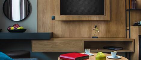 A modern living room with a round wooden table, a red book, a pear, and a cup.