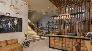 A modern hotel lobby with a wooden reception desk, a staircase, and a sofa. - The Stay by Aston (Plovdiv)