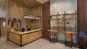 A reception area with a wooden reception desk, a vertical wooden panel wall, and a shelf with various items. - The Stay by Aston (Plovdiv)
