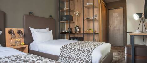 A hotel room with two beds, a desk with a lamp, a safe, and a minibar.