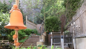 Un jardín con una campana, escalones y una valla de madera.