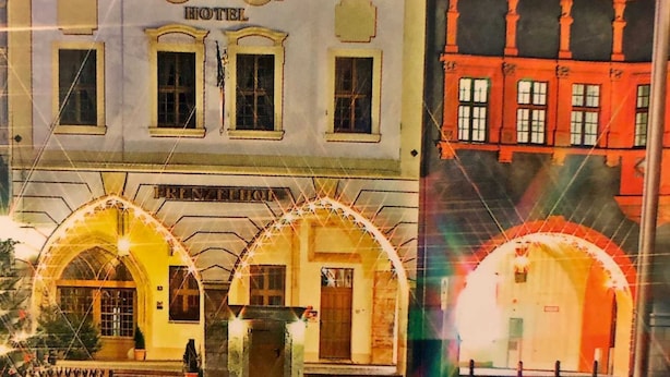 Un hotel con entrada central, varias ventanas y un cartel sobre la entrada.