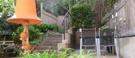 A garden with a bell, steps, and a wooden fence.