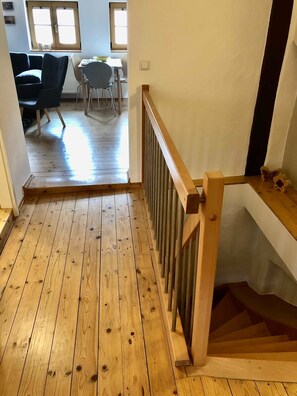 A wooden staircase leading to a landing with a view of a dining area. - Landeskrone loft maisonette - Altstadthaus / Ferienwohnungen Görlitz (Görlitz)
