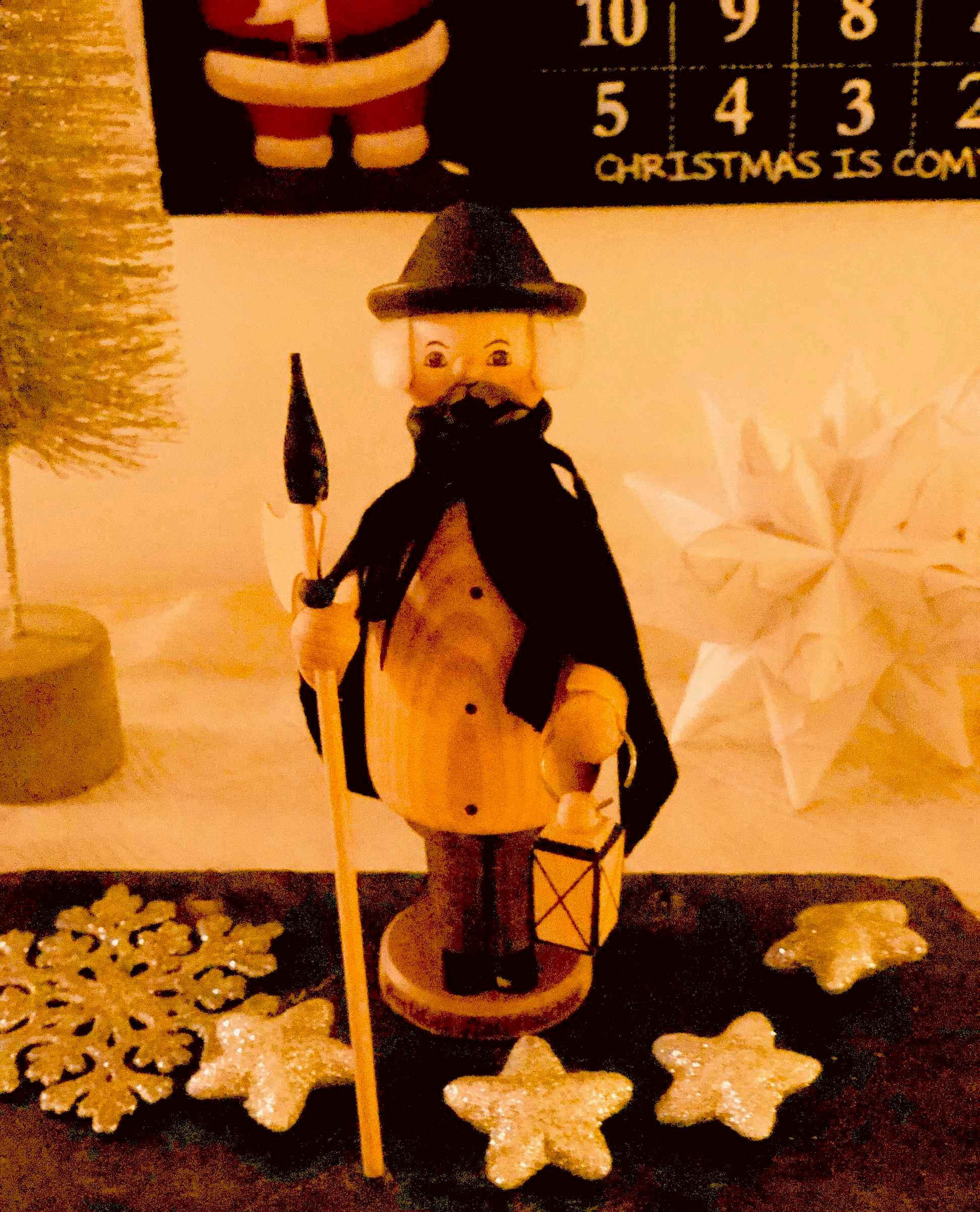 A snowman figurine with a hat, a staff, and a scarf, surrounded by star-shaped decorations and a calendar with 'CHRISTMAS IS COMING' text.