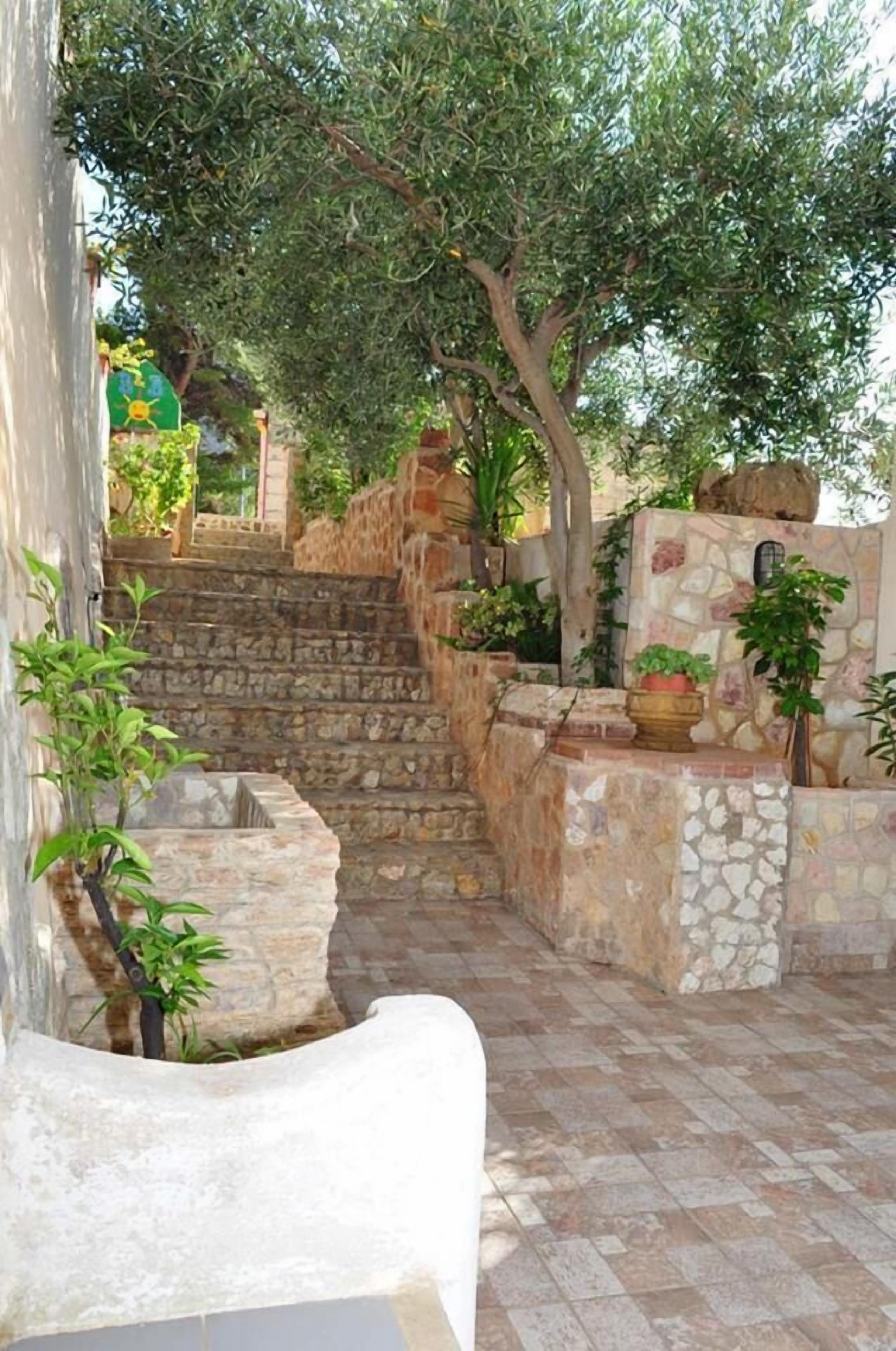 A stone staircase leading up to a stone wall with potted plants.