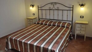 A bedroom with a bed, two bedside tables, and wall-mounted lamps. - Verde Mare (San Vito Lo Capo)