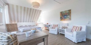En moderne stue med et træbord, hvide sofaer og et stribet loft.