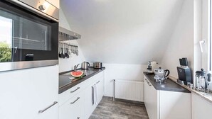 A modern kitchen with white cabinets, a black countertop, and a window providing natural light.