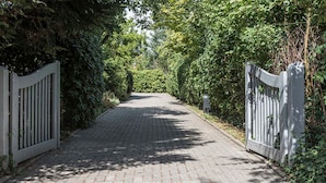A paved pathway flanked by white gates, surrounded by dense greenery.