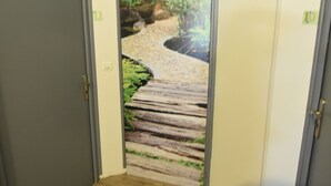 Un pasillo con piso de madera que conduce a una puerta decorada con un mural de temática natural.