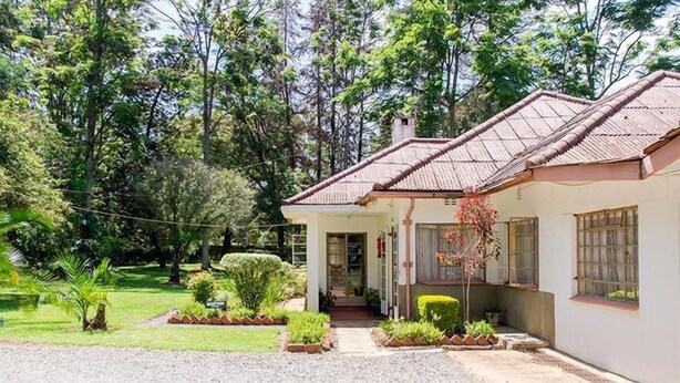 A single-story house with a tiled roof, surrounded by a well-maintained garden and trees. - Kenmosa Resort (Eldoret)