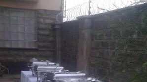 A buffet setup with multiple serving stations covered by white tablecloths, arranged outdoors with a brick wall and greenery in the background. - Kenmosa Resort (Eldoret)