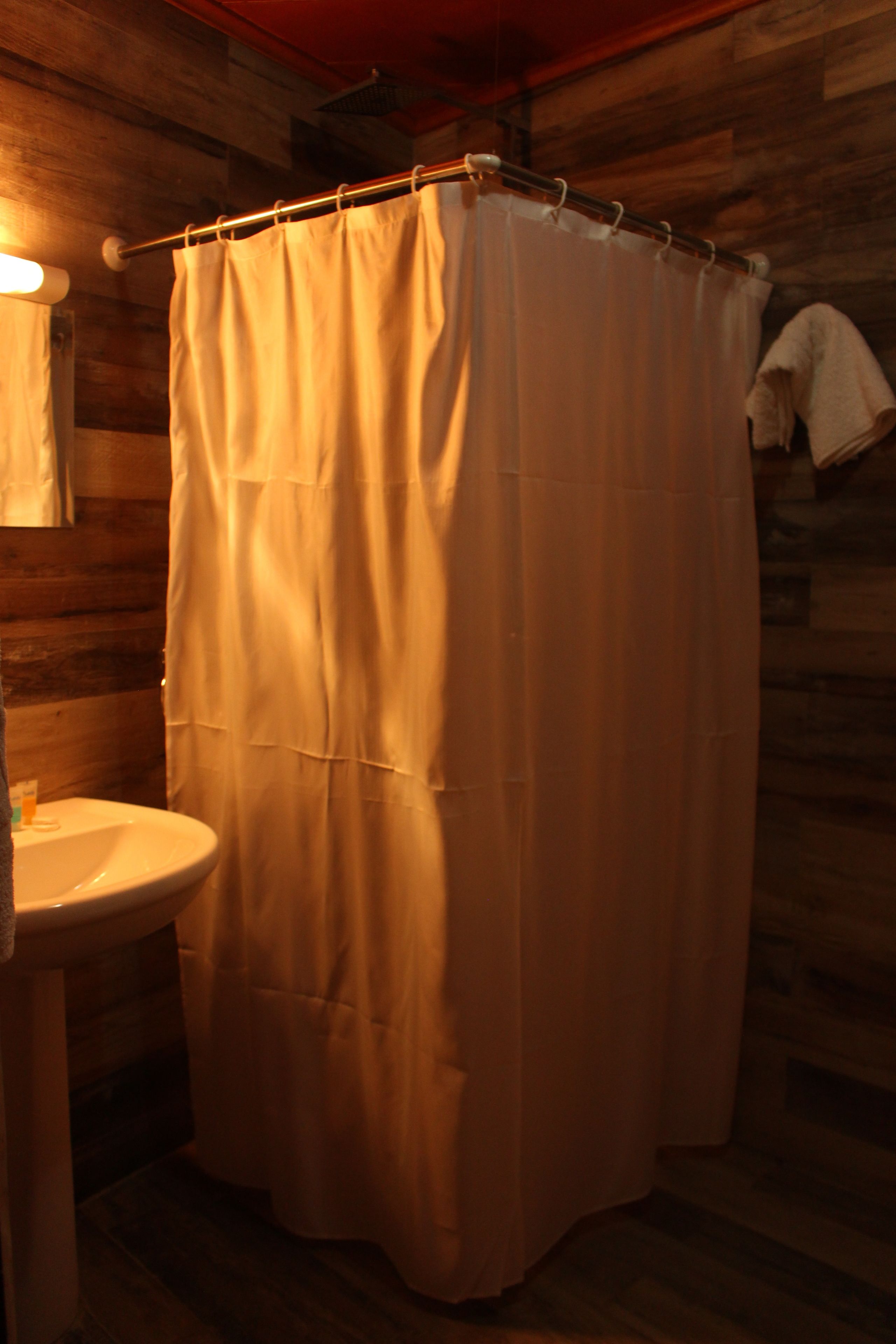 Un baño con detalles de madera, un lavamanos blanco y una cortina de ducha.