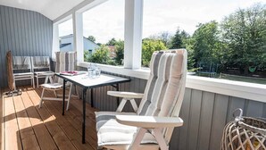 Un espacio al aire libre cubierto con una mesa y sillas, vistas a la vegetación y una barandilla.