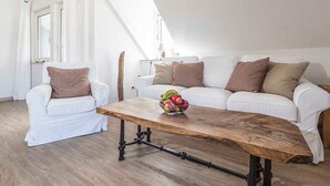 Una sala de estar moderna con un sofá blanco, una mesa de centro de madera y un sillón blanco.