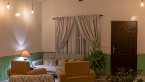 Un salon comprenant un canapé, deux fauteuils, un ventilateur de plafond et une porte.