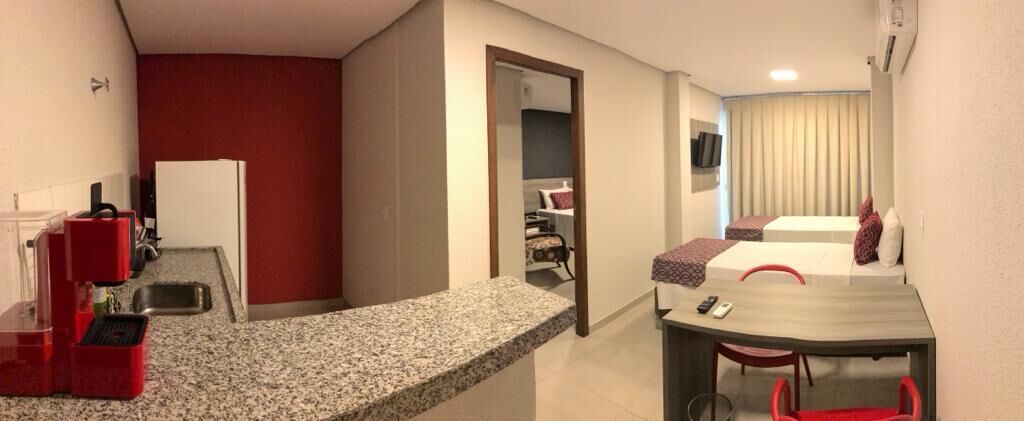 A compact hotel room with a kitchenette, a dining area, and a bed.