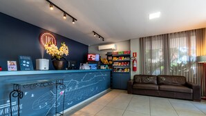 Zona de recepción de hotel con mostrador, equipo de aire acondicionado y sofá.