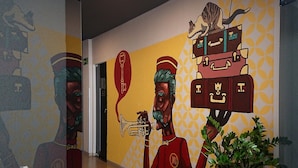 Un pasillo con un mural que muestra a un hombre sosteniendo una trompeta, una maleta y un gato sobre una pila de maletas.