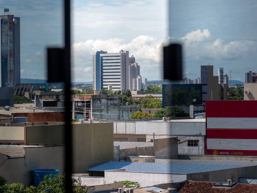 Un hôtel avec une enseigne rouge et blanche, entouré de bâtiments urbains et de verdure.