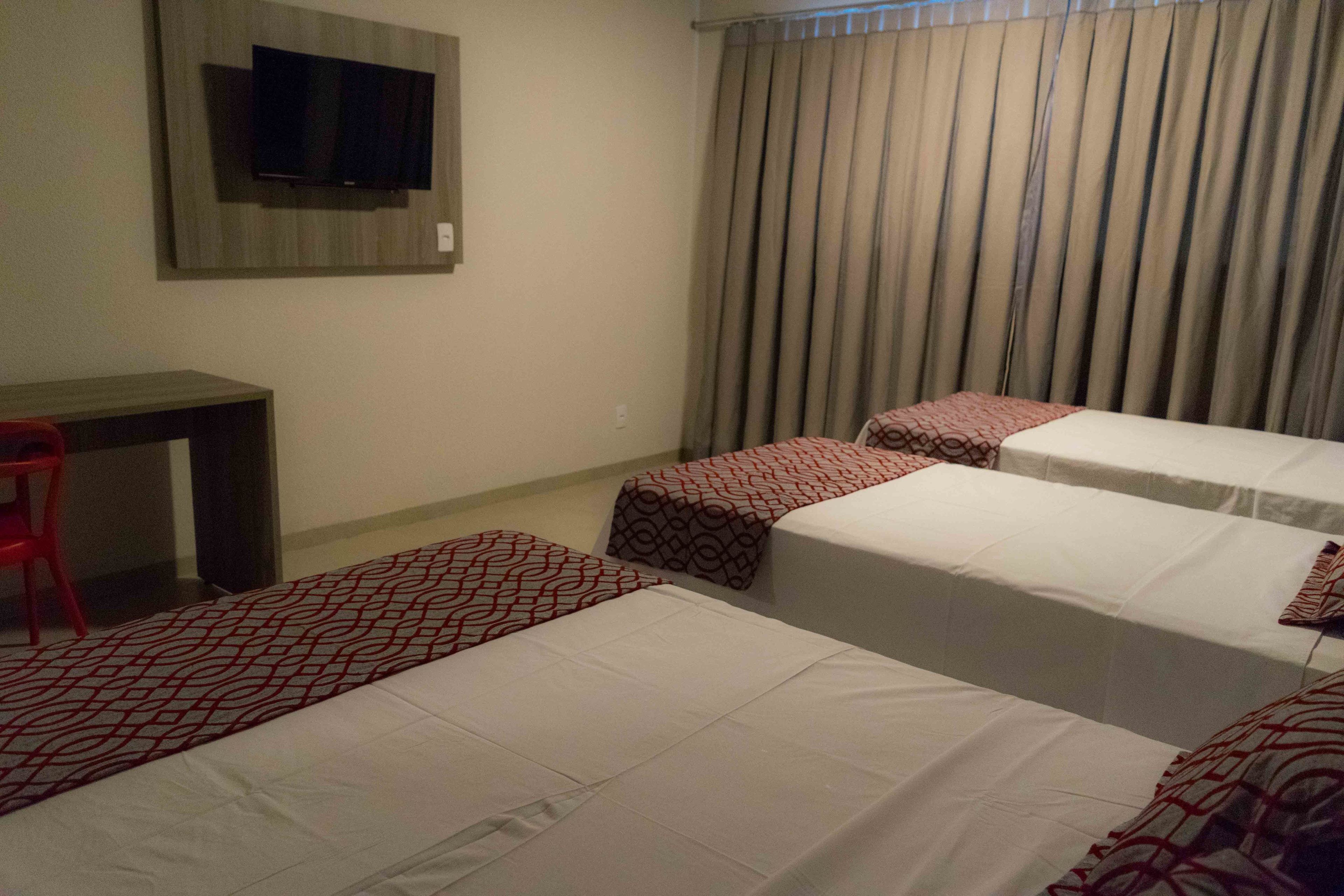 Une chambre d’hôtel avec deux lits, un bureau et un téléviseur fixé au mur.