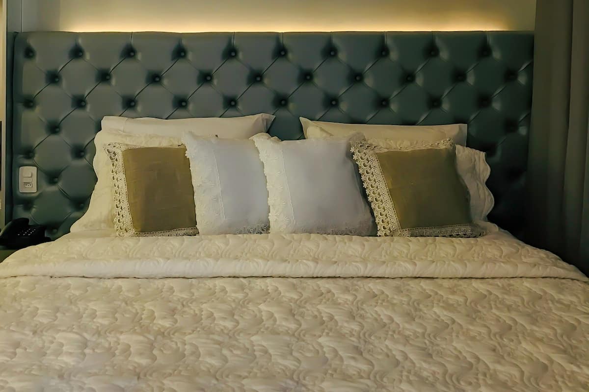 A neatly made bed with a tufted headboard, white linens, and decorative pillows.