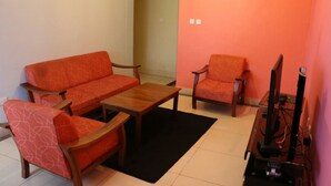 A living room with a sofa, armchairs, a coffee table, and a TV stand. - Ridge Apartments (Eldoret)