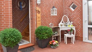 A brick building with a wooden sign reading "MOTEL," a white door, and a small white table with a mirror and decorative items. - Apartment - Apartment Sonnenberg, 25502 (Weener)