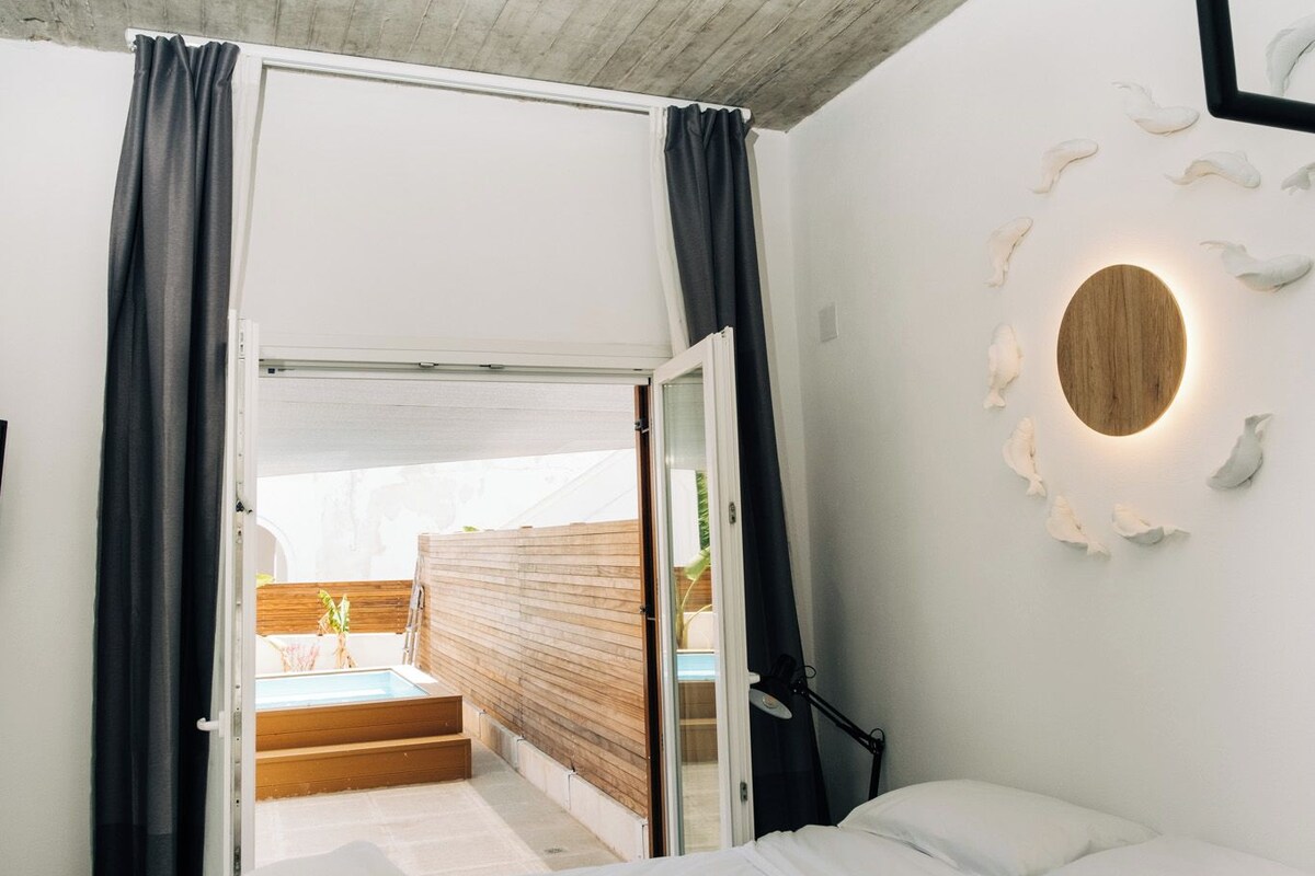 A modern bedroom with a large bed, a wooden ceiling, and a circular wall light.