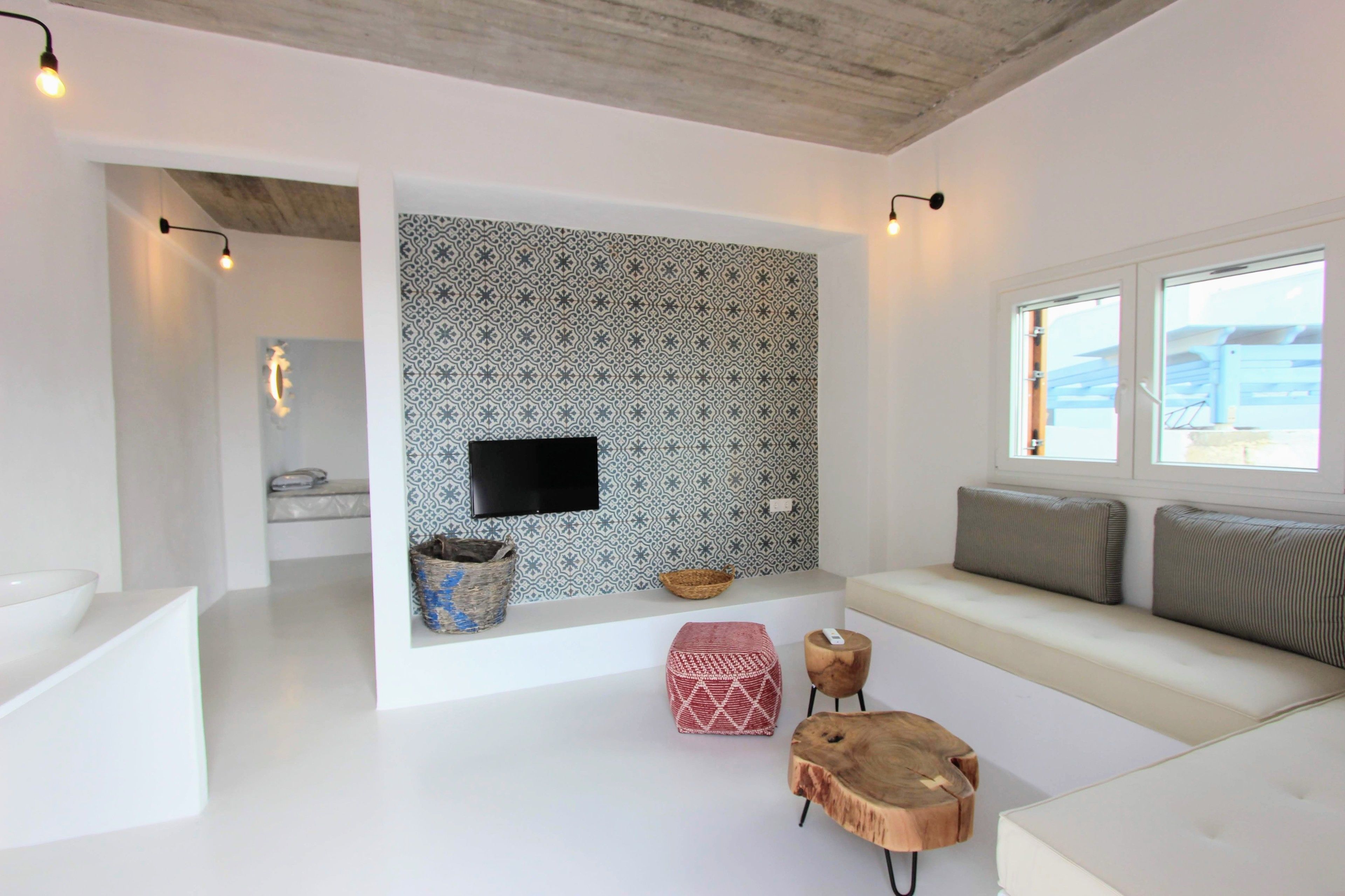 A modern living room with a patterned wall, a flat-screen TV, a sofa with cushions, a wooden coffee table, and a small side table.