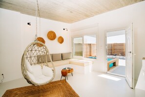 Una sala de estar moderna con un sillón colgante, un sofá y vistas a una piscina al aire libre.