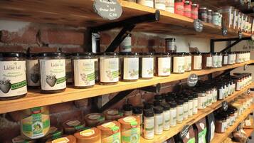 A variety of food products on wooden shelves, including jars of preserves and honey.